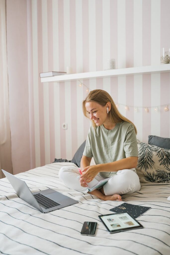 Szkoła Językowa Lagarta Woman enjoying an online education session while seated comfortably on her bed, using a laptop.