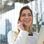 Szkoła Językowa Lagarta Confident businesswoman using her tablet and phone, smiling outdoors in sunlight.